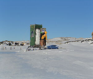 An expeditioner checks out the snow-filled toilet at the Wilkes Hilton