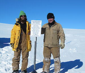 Expeditioners stand near the sign they have just re-erected