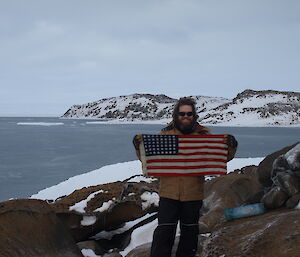 Steve Hankins holding the small American flag that is in the cache on Petersons Is marking and American landing site