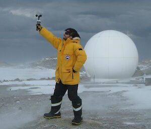 Daniel Laban taking a wind reading with the X-band satellite dome in the background