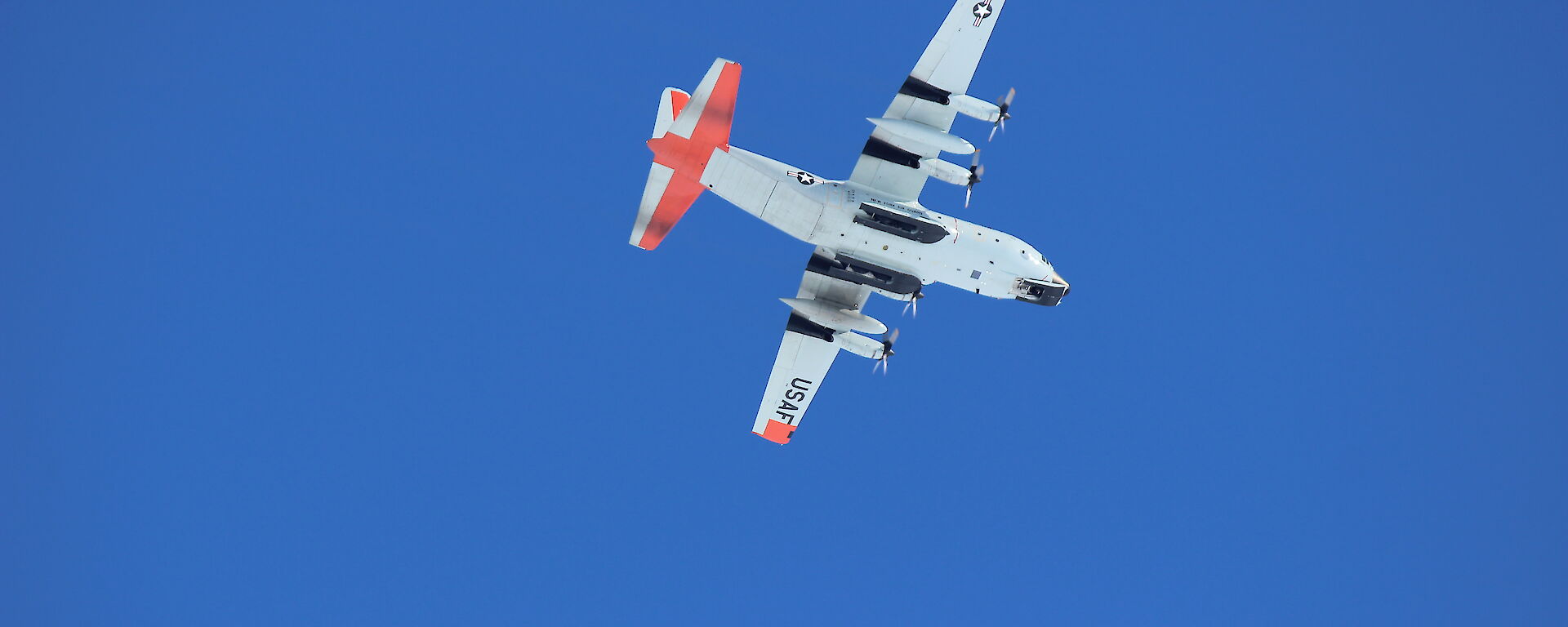 Photo of a C-130 Hercules from below, flying over Casey Skiway