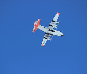 Photo of a C-130 Hercules from below, flying over Casey Skiway