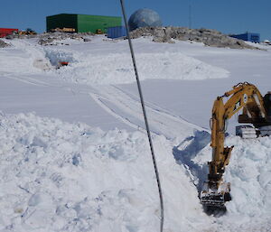 Two peices of earthmoving machinery and their operators hard a work excavating road out of the white snowdrift