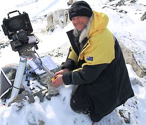 An expeditioner maintains a penguin photographing time lapse camera, near Whitney Point