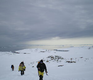 A group of expeditioners walks up the hill from the Shirley Island sea ice, returning to station.