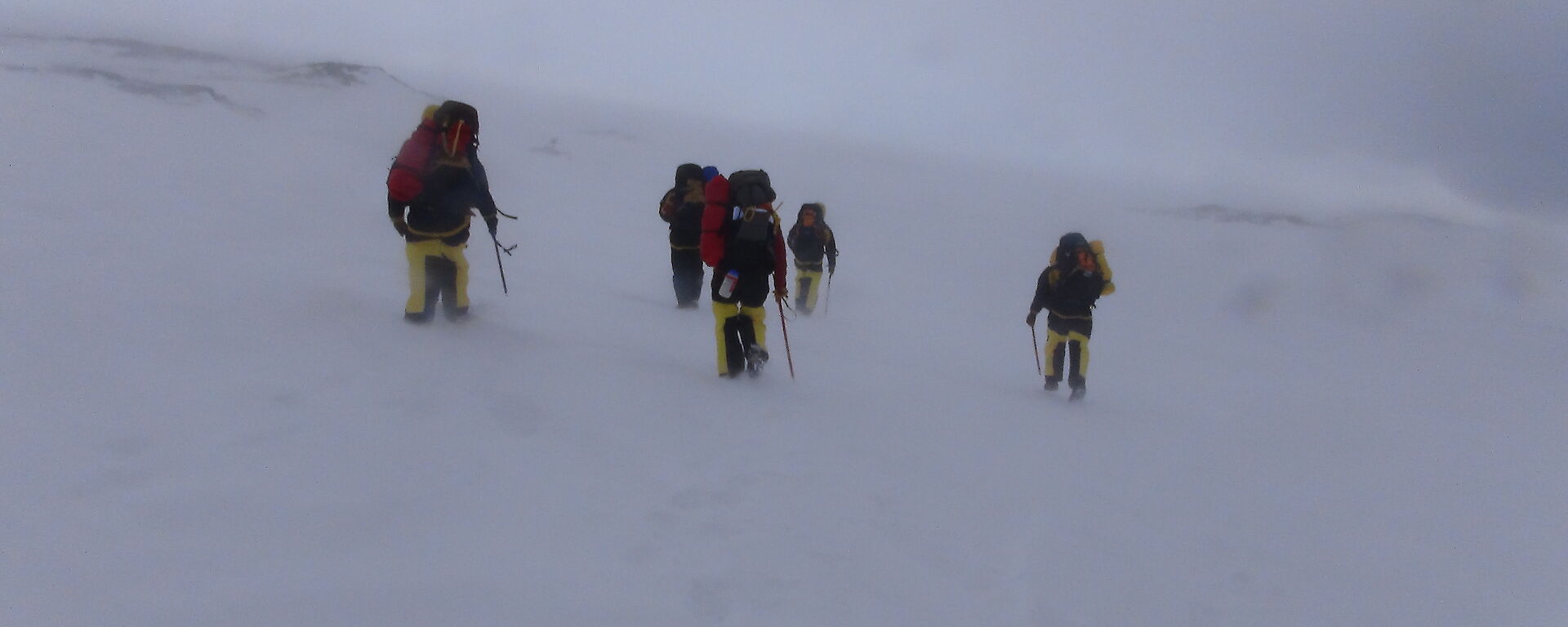 A group of expeditioners walks to the survival camp in approaching poor weather