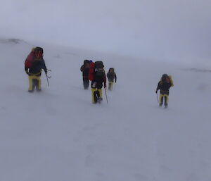 A group of expeditioners walks to the survival camp in approaching poor weather