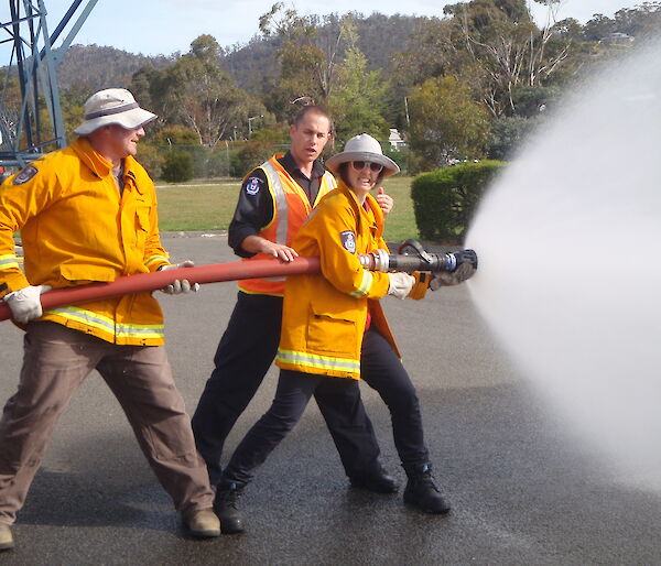 Two expeditioners being taught to use a fire hose