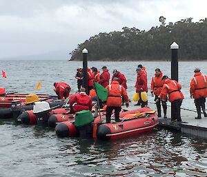 A number of inflatable rubber boats and their crews tied to a wharf