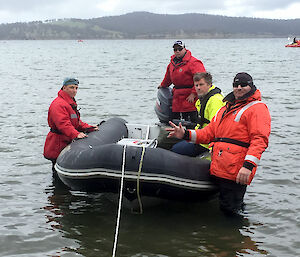 Four expeditioners in an inflatable rubber boat getting ready