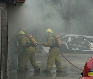 Two expeditioners wearing full BA equipment entering a smoke filled building,