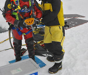 A diver in full suit with his tender getting ready for a dive