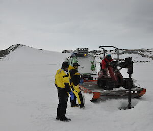 A large drill machine on the ice drilling a hole for the diver to enter the water