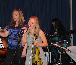 A female singer enthusiastically singing at a microphone