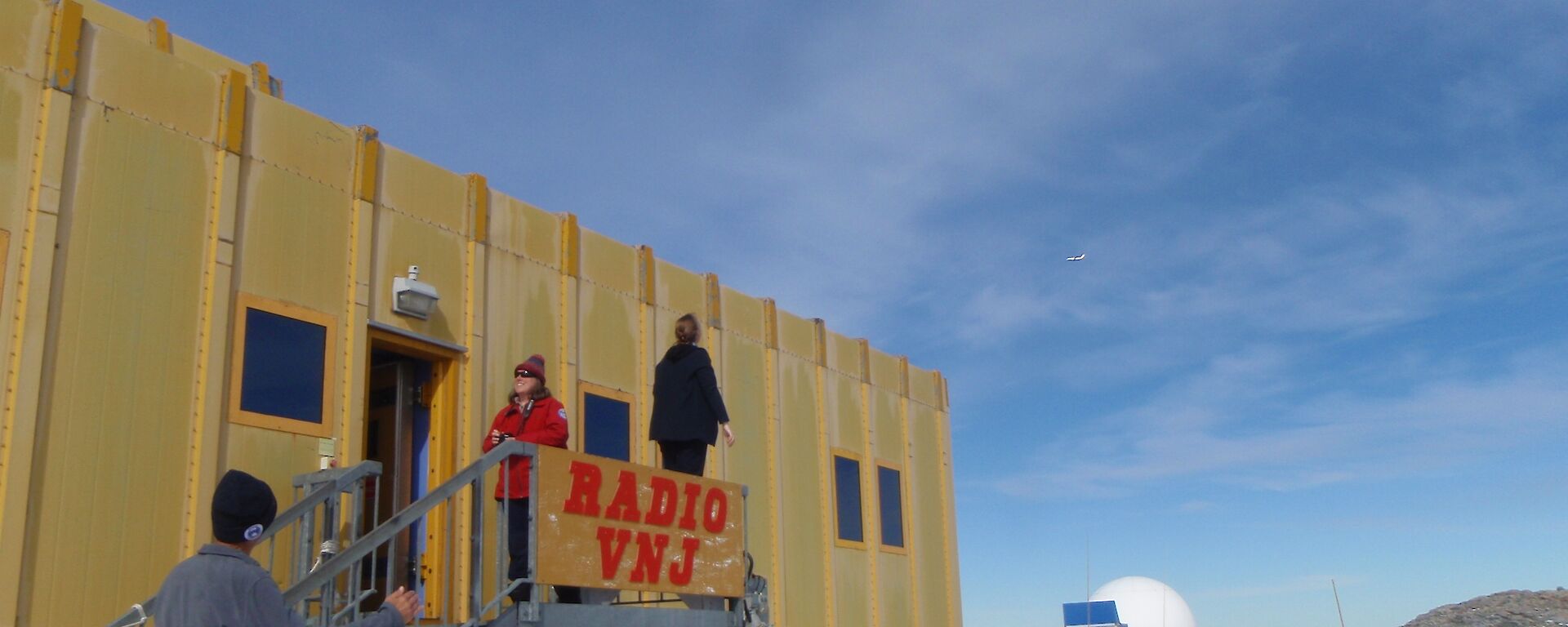An expeditioner looking for a plane in the sky while it flies behind her