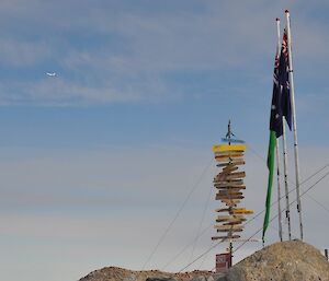 A plane flying over Casey station’s sign and flags
