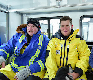 Two expeditioners sitting in the back seat of a snow tractor