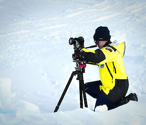 An expeditioner setting up a camera & tripot in the ice