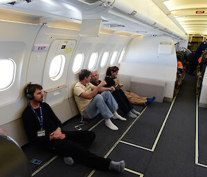 Several expeditioners seated on the floor in the plane