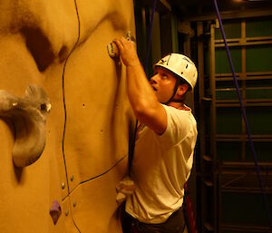 An expeditioner high on the crux of the climbing wall.