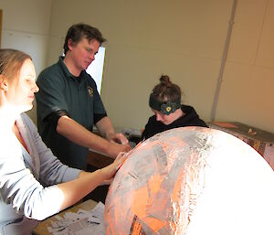 The beginning of the piñata with people and a ball of papier mache