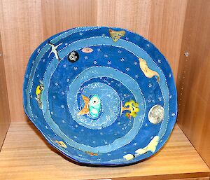 A blue painted ceramic bowl with a sea theme