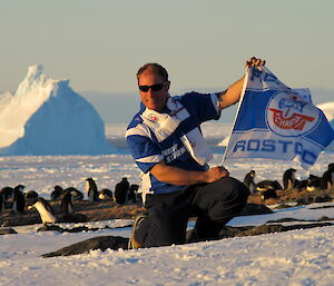 Man on the ice in sports team shirt and holding up team flag
