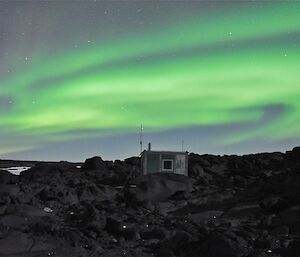 The Aurora Australis fills the sky. Bandits hut in the foreground