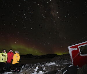 Darryl Seidel, Steph MacDonald, Joe Glacken outside Watts Hut with aurora in background