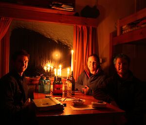 Darryl Seidel, Steph MacDonald, Joe Glacken pose inside Watts Hut in candelight