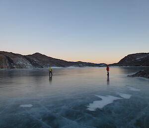 Watts Lake frozen solid from a distance with two expeditioners on the ice