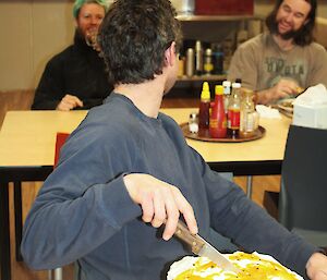 Joe Glacken birthday at Davis 2012 cuts his cake while looking back at other expeditioners