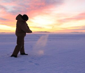 Davis Golf Game 2012. Action shot of expeditioner swinging golf club and snow coming up off the ice