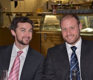 Head shot of two men in suits smiling at camera.