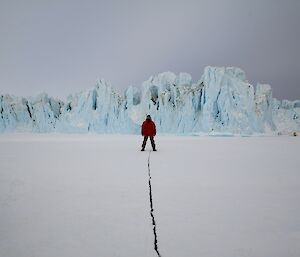 Expeditioner standing over a tide crack in ice