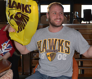 Man in Hawthorn team shirt holding inflatable hand