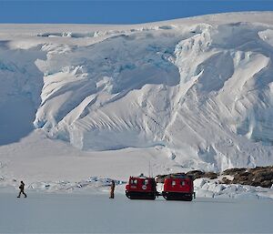 The edge of Antarctica with a hagg and two expeditioners dwarfed by ice