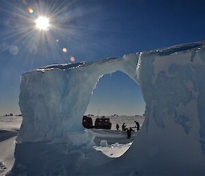 Landscape and sun seen through a round hole in an iceberg
