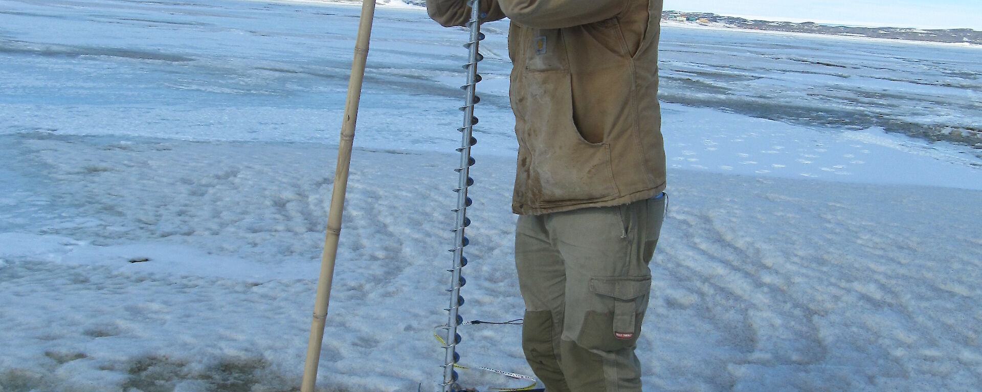 Adam Christensen drilling the sea ice