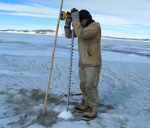 Adam Christensen drilling the sea ice