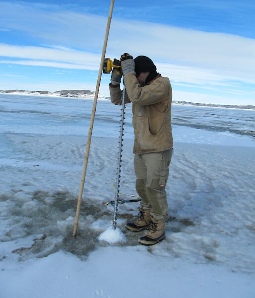 Adam Christensen drilling the sea ice