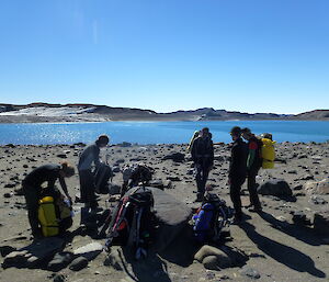 Eight expeditioners stopping for a rest near an Antarctic lake