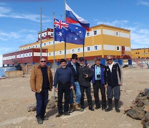 Group of Australian & Russian expeditiners pose for a photo in front of the flag pole