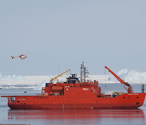 Helicopters sling loading cargo from ship to shore at Davis over open water