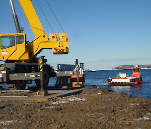 A crane on the Davis wharf lifting cargo from a barge