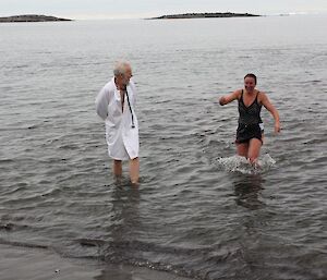 Station doctor in his white coat and ankle-deep in the water looking after the swimmers