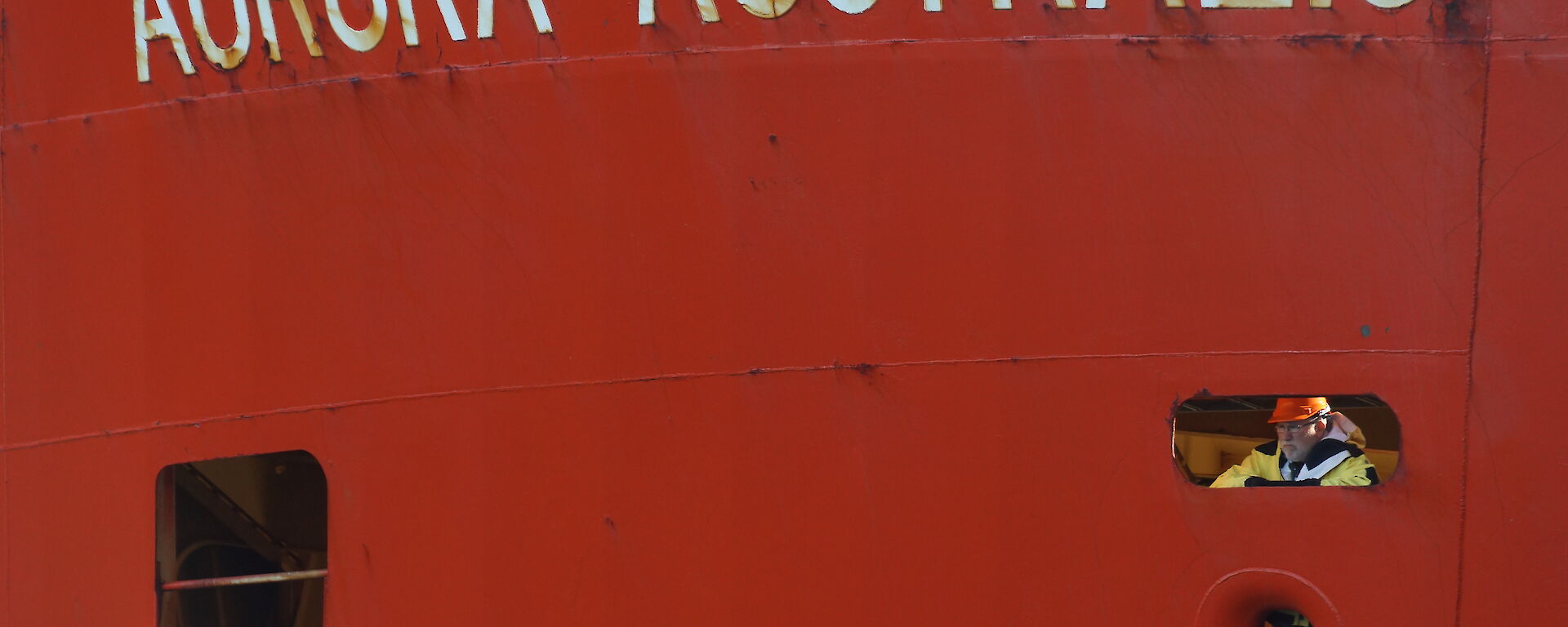 Voyage leader looking out port hole of the Aurora Australis