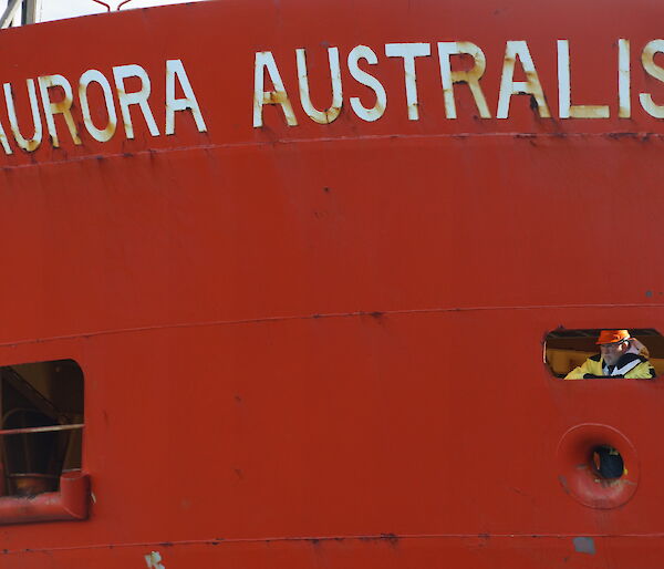 Voyage leader looking out port hole of the Aurora Australis