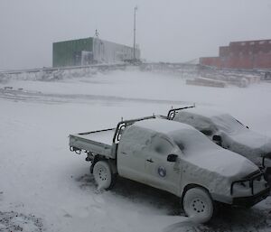 Two utes covered in snow that will require the snow to be removed before being used.