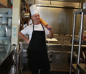 Rondney in the kitchen with his chef hat on and holding a rolling pin